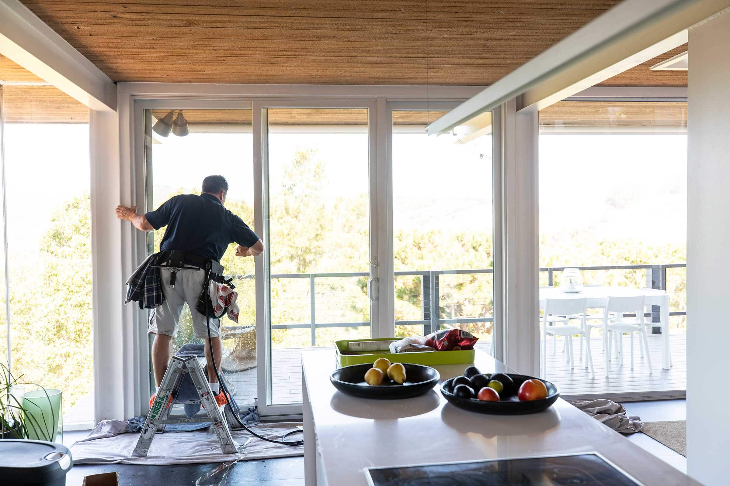 Window film installer applying window film in a home